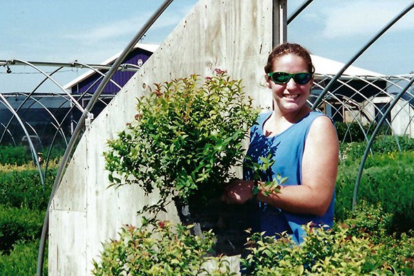 Photo of a woman in a blue shirt holding a potted plant