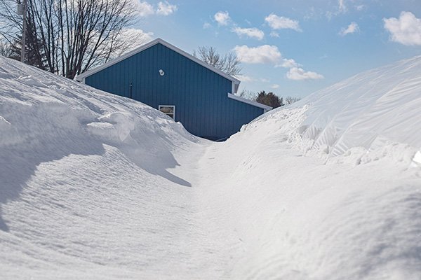 Photo of snow piled up against grey building